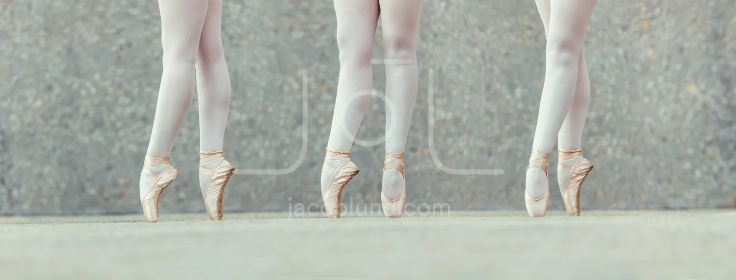 Closeup of legs of three ballet dancers in pointes