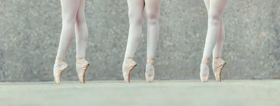Closeup of legs of three ballet dancers in pointes